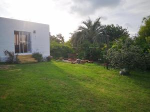 un patio con una casa blanca y un campo de césped en Adorable microcasa a 4km del centro de Maldonado y de playa mansa, en barrio muy tranquilo!, en Maldonado