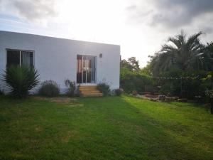 a white house with a lawn in front of it at Adorable microcasa a 4km del centro de Maldonado y de playa mansa, en barrio muy tranquilo! in Maldonado