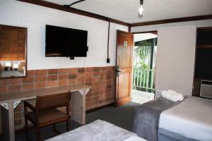 a hotel room with a bed and a desk and a television at Soy Local San José in San José