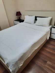 uma cama grande com lençóis brancos e almofadas em Large apartment in Tbilisi em Tbilisi