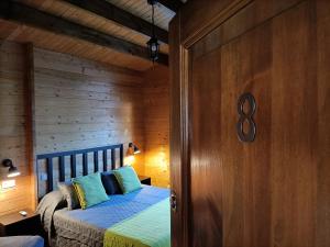 1 dormitorio con 1 cama y pared de madera en La Dehesa2 de Toledo, en Cobisa