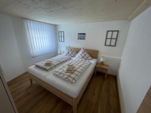 a bedroom with a large bed with white walls and wooden floors at Chasa Diana in Samnaun