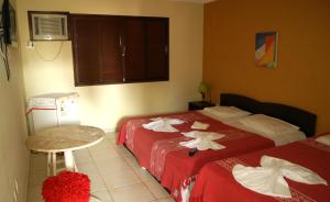 a hotel room with two beds and a table at Hospedaria Lua Raio de Sol in Natal