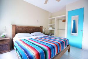1 dormitorio con 1 cama con una manta a rayas de colores en Casa de Colores en Playa del Carmen