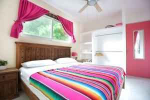1 dormitorio con cama de arco iris y ventana en Casa de Colores en Playa del Carmen