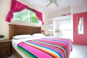 a bedroom with a rainbow bed with a window at Casa de Colores in Playa del Carmen