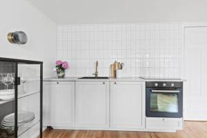 een witte keuken met een wastafel en een fornuis bij Central studio apartment in Reykjavík
