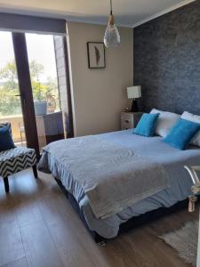 um quarto com uma cama grande e almofadas azuis em Costanera Playa Villarrica em Villarrica