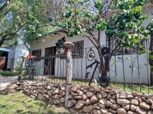 une maison avec une clôture et un mur en pierre dans l'établissement El Escarabajo Azul loft & Arte, à Villa Carlos Paz