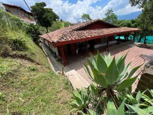 une maison avec un toit en tuiles rouges sur une colline dans l'établissement Casa Finca San Nicolas, à Sabaneta