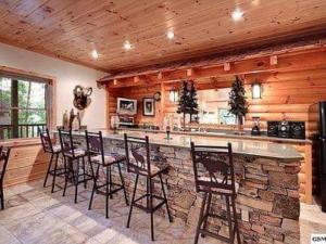 a bar in a kitchen with wooden walls and chairs at Providence Cabin in Townsend