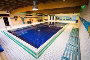 a large swimming pool with two benches in a building at Gezellige vakantiewoning met sauna in Ewijk bij Nijmegen - recreational only no workers in Ewijk