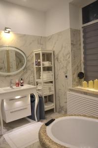 ein Badezimmer mit einer Badewanne, einem Waschbecken und einem Spiegel in der Unterkunft Gemütliche Apartment Lucky und Lucky de Luxe in Bremerhaven