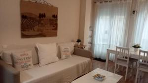 een woonkamer met een witte bank en een tafel bij EnFOZ PLAYAS ÚNICAS Y DIVINAS! in Foz
