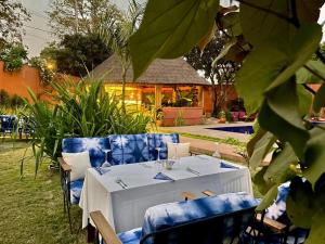 uma mesa e cadeiras com uma toalha de mesa branca e copos de vinho em Le Kentia em Lomé