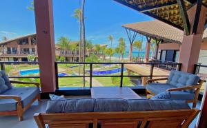 uma varanda com 2 sofás e vista para uma piscina em Dream Beach Cumbuco Superior Oceanfront Apartments em Cumbuco