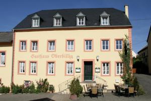 un grand bâtiment jaune avec un toit noir dans l'établissement Landgasthaus Oberbillig, à Holsthum