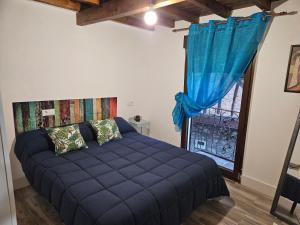 Un dormitorio con una cama azul y una ventana en Casa Cefita, en Madroñal