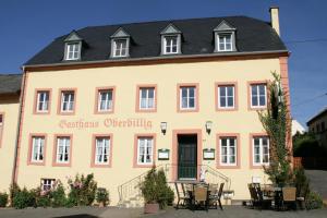 un grand bâtiment jaune avec un toit noir dans l'établissement Landgasthaus Oberbillig, à Holsthum