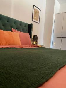 ein Schlafzimmer mit einem grünen Bett und orangefarbenen Kissen in der Unterkunft Stylish flat close to Basel with a stunning view in Weil am Rhein