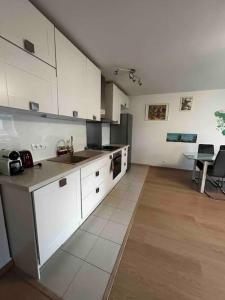 a large kitchen with white cabinets and a table at Appartement 3 chambres avec parking, près d’Orly in Antony