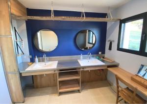 een badkamer met 2 wastafels en 2 spiegels bij L’écrin des bois in Mansac