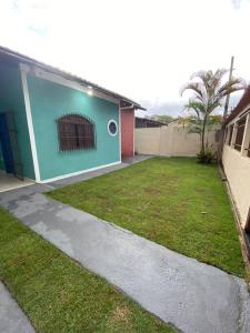 a house with a yard in front of a building at Casa Excelente Praia Grande in Fundão
