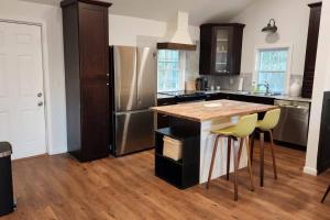 a kitchen with a wooden table and a stainless steel refrigerator at Town-Center Sanctuary:Cozy 3BD for Relocation in Duncan
