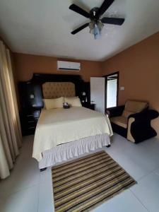 a bedroom with a bed and a fan and a chair at Home Away From Home 