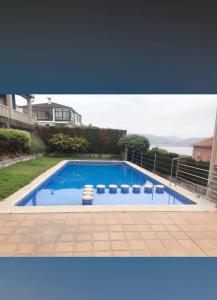 a large blue swimming pool with a house in the background at Piso Beiramar in Pontevedra