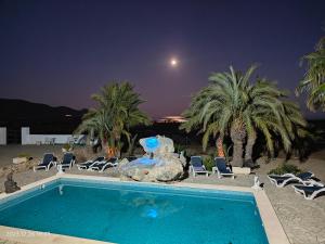 una piscina con sillas y palmeras por la noche en CampoMar en Los Escullos
