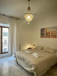 een slaapkamer met een groot bed met een kroonluchter bij Domus Massimiliani Guesthouse in Rome