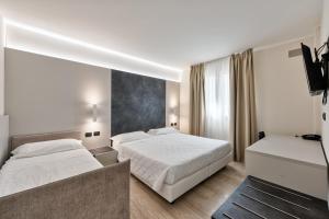 a bedroom with two beds and a flat screen tv at Columbus Dependance in Lignano Sabbiadoro