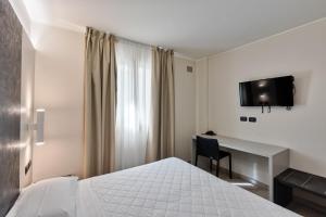 Habitación de hotel con cama y escritorio en Columbus Dependance, en Lignano Sabbiadoro