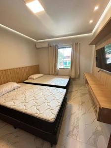 1 dormitorio con 2 camas y TV. en Casa Temporada Villagio Del Mare, en Salinópolis