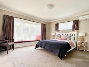 um quarto com uma cama e uma grande janela em Private Cosy House in Chartwell, Hamilton, Near Everything em Hamilton