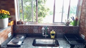 eine Küchentheke mit einem Waschbecken und einem Fenster in der Unterkunft Chalé no morro in Ubatuba