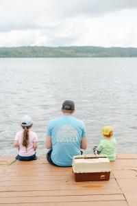 a man and two children sitting on a dock at Deluxe Glamping Tents at Lake Guntersville State Park in Guntersville