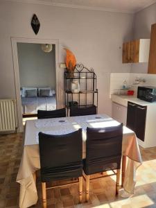 eine Küche mit einem Tisch und einigen Stühlen sowie eine Küche mit einer Küche in der Unterkunft Maison de campagne avec jardin près du Périgord in Mansac