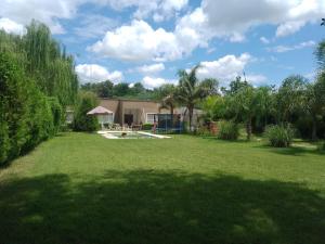een tuin met een huis en een groot gazon met bomen bij 4 hijos in La Banda