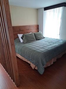 1 dormitorio con 1 cama con cabecero de madera y ventana en Acogedor Apartasuite cerca al Parque de la 93, en Bogotá