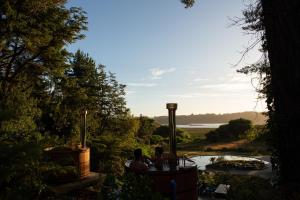 two people sitting in a hot tub overlooking a river at Hotel Puerta del Sur in Valdivia