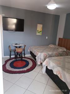 a room with two beds and a table and a tv at Condominio Residencial Thermas Place in Caldas Novas