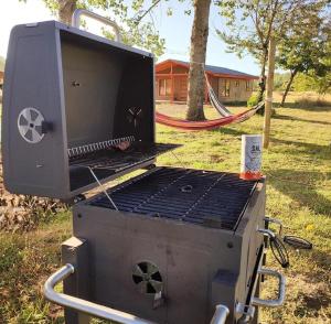 a grill in the grass with a playground in the background at Cabaña Refugio Eluney in Villarrica