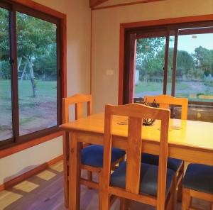 uma sala de jantar com uma mesa de madeira e cadeiras em Cabaña Refugio Eluney em Villarrica