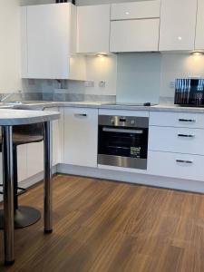 eine Küche mit weißen Schränken und einem schwarzen Backofen in der Unterkunft Stunning 2-Bed Apartment in Grays in West Thurrock