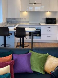 Stunning 2-Bed Apartment in Grays في ثوروك الغربية: أريكة زرقاء مع وسائد ملونة في المطبخ