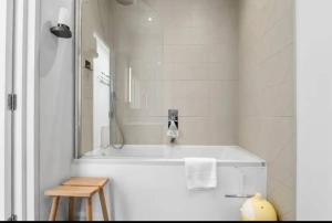 a bathroom with a tub with a mirror and a stool at Luxury modern flat near ExCel, 02 & Canary Wharf in London