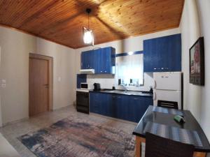 uma cozinha com armários azuis e um frigorífico branco em Olympia Project / Χώρος Διαμονής στην Αλμωπία em Exaplátanos