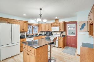 a kitchen with wooden cabinets and a white refrigerator at Lakefront Minnesota Vacation Rental with Dock in Annandale